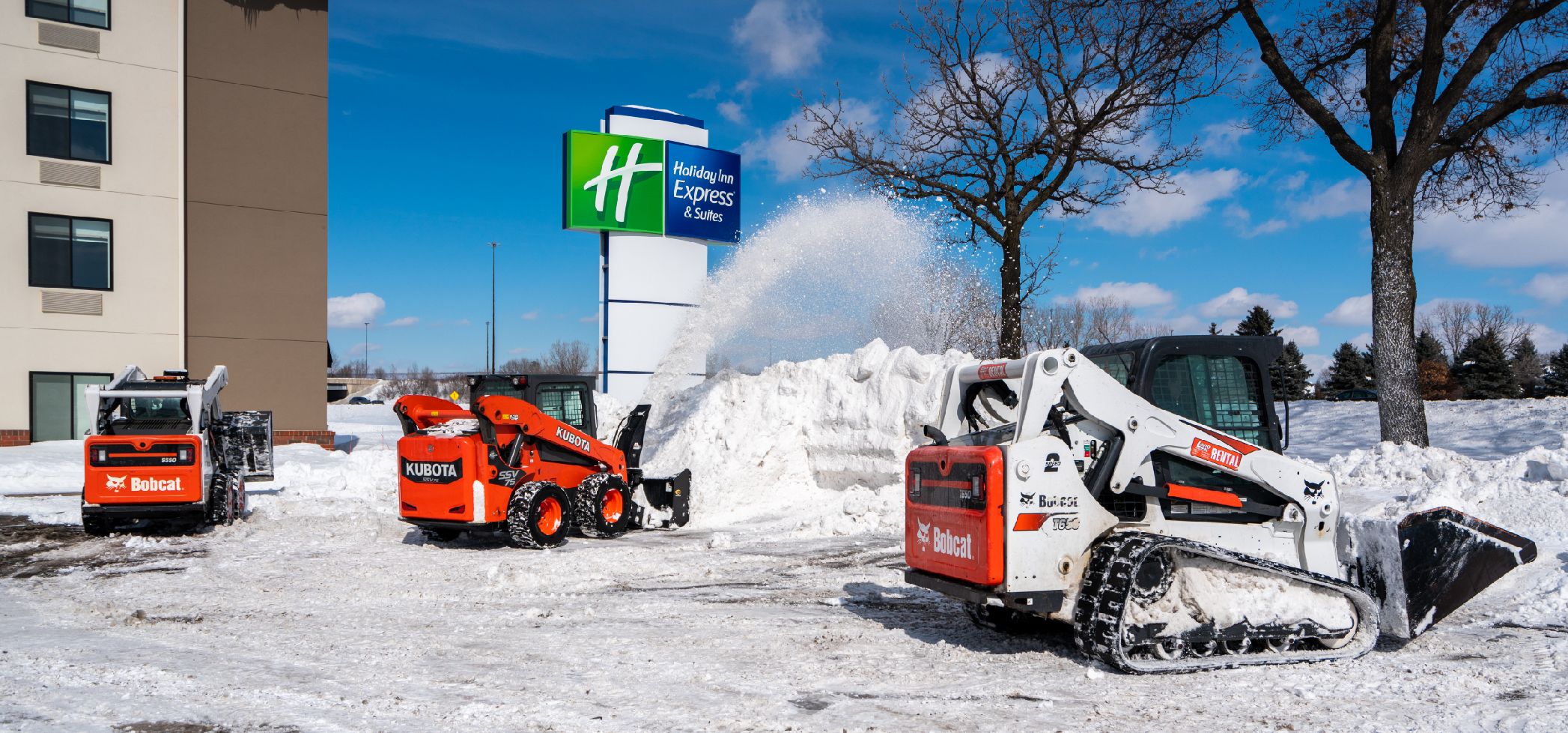 Commercial snow removal with Bobcat and Kubota machines clearing a parking lot